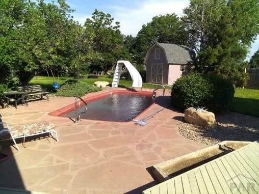 view of swimming pool featuring a patio area, a storage shed, a water slide, and an outbuilding