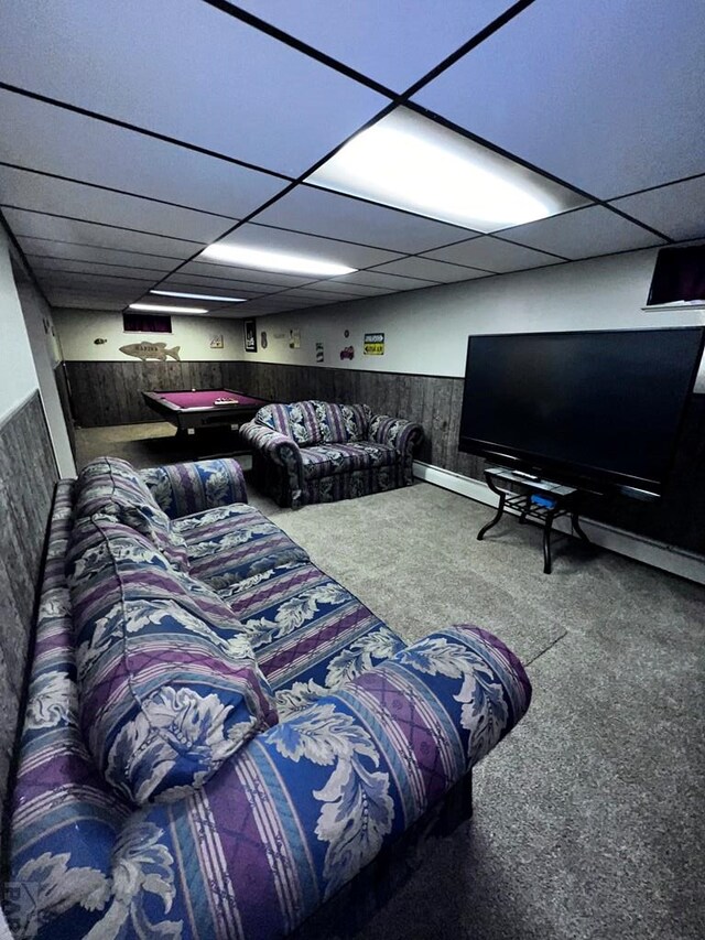 carpeted living room featuring a wainscoted wall, wooden walls, a drop ceiling, and pool table