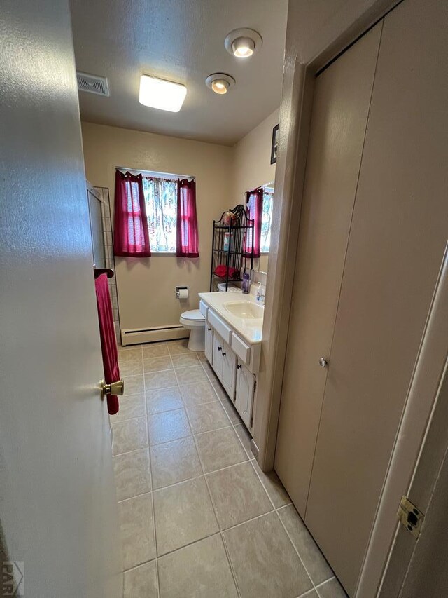 bathroom with visible vents, toilet, baseboard heating, vanity, and tile patterned flooring