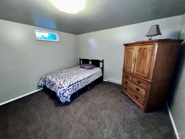 bedroom with a baseboard radiator, dark carpet, and baseboards