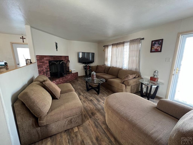 living room featuring dark wood-type flooring, plenty of natural light, and a brick fireplace