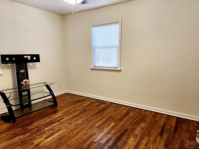 interior space with dark wood-style flooring, visible vents, ceiling fan, and baseboards