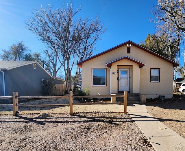 view of front facade with crawl space, fence, and stucco siding