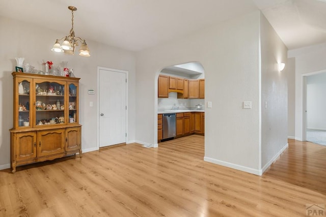 2330 Inspiration Ln, Pueblo, CO 81008 - unfurnished dining area featuring light wood finished floors, arched walkways, a chandelier, and baseboards