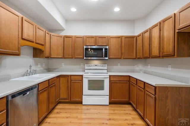 2330 Inspiration Ln, Pueblo, CO 81008 - kitchen with stainless steel appliances, a sink, light wood finished floors, brown cabinets, and recessed lighting