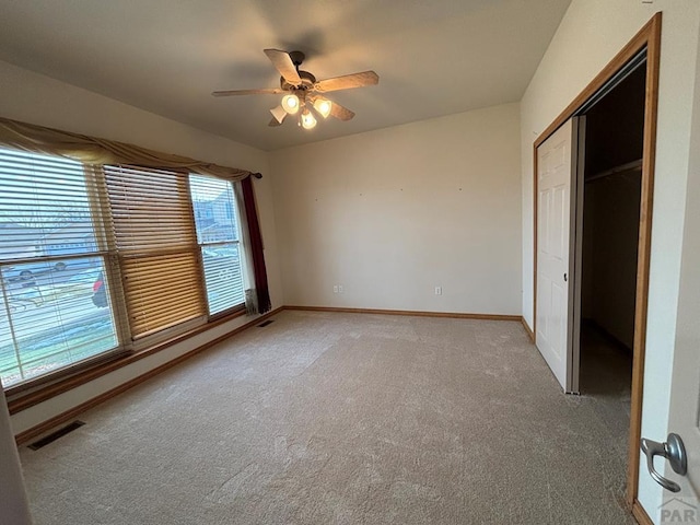 unfurnished bedroom with a closet, light colored carpet, visible vents, a ceiling fan, and baseboards