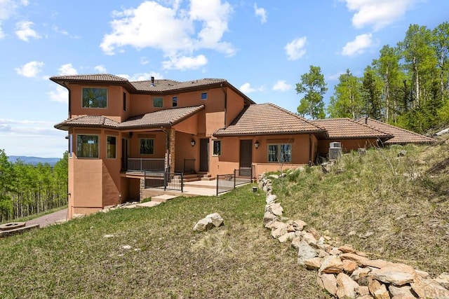 back of house with a tile roof, a patio area, and stucco siding