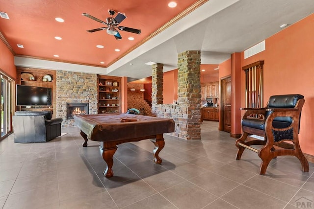 recreation room with a fireplace, visible vents, a ceiling fan, decorative columns, and crown molding