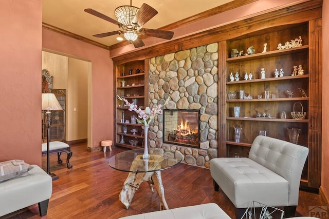 living room with a fireplace, wood finished floors, baseboards, built in features, and ornamental molding