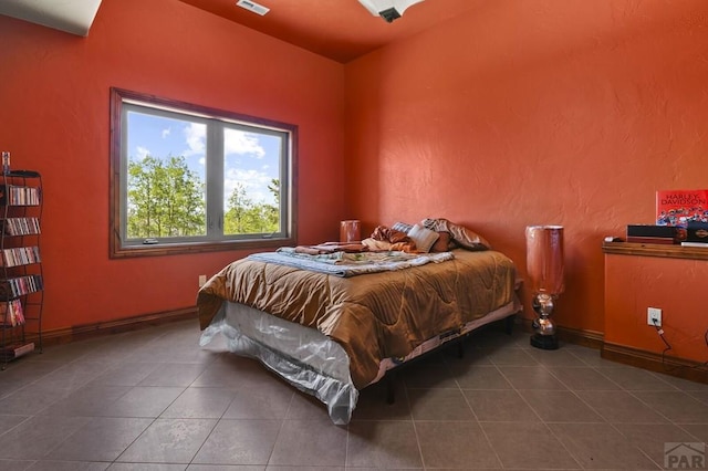 bedroom with dark tile patterned floors, visible vents, and baseboards