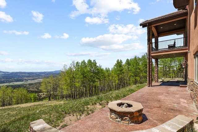 view of patio / terrace with a fire pit and a balcony