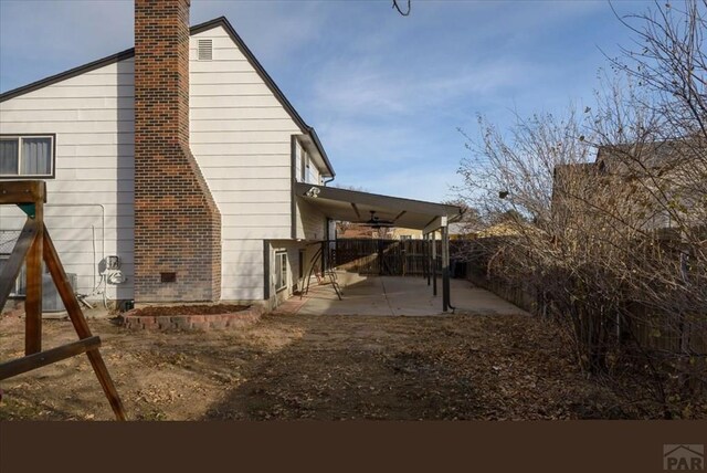 view of side of home with a patio, a chimney, and fence