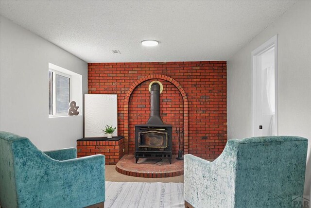 sitting room featuring a textured ceiling, brick wall, and a wood stove