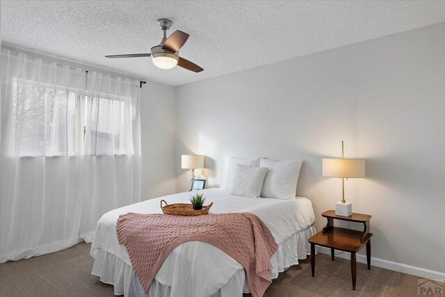 carpeted bedroom with a ceiling fan, a textured ceiling, and baseboards