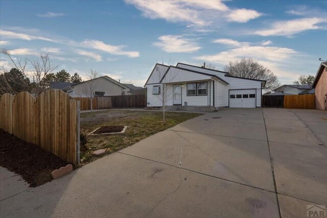 view of front of house with driveway, a front lawn, an attached garage, and fence