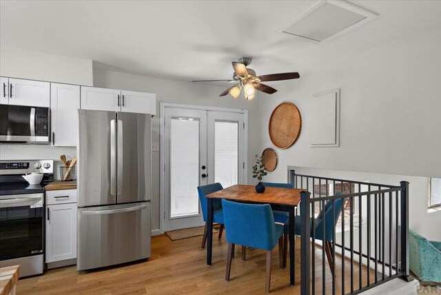 kitchen featuring french doors, stainless steel appliances, dark countertops, light wood-style floors, and white cabinetry