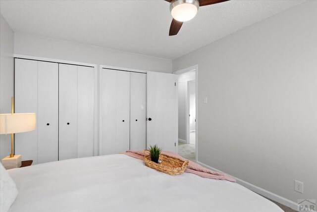 bedroom featuring ceiling fan, baseboards, and multiple closets