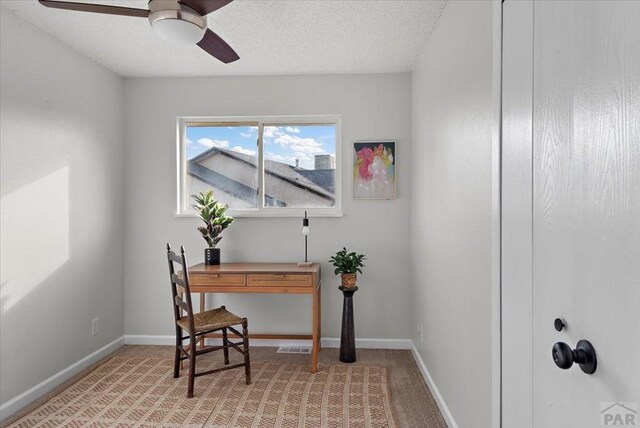 home office featuring a ceiling fan, baseboards, a textured ceiling, and light colored carpet