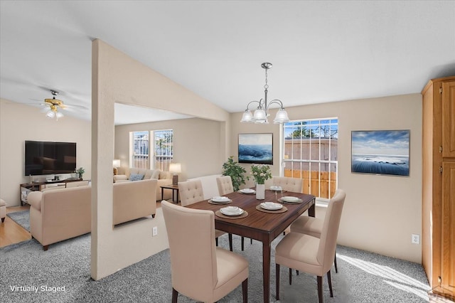 dining area featuring vaulted ceiling, carpet floors, and ceiling fan with notable chandelier