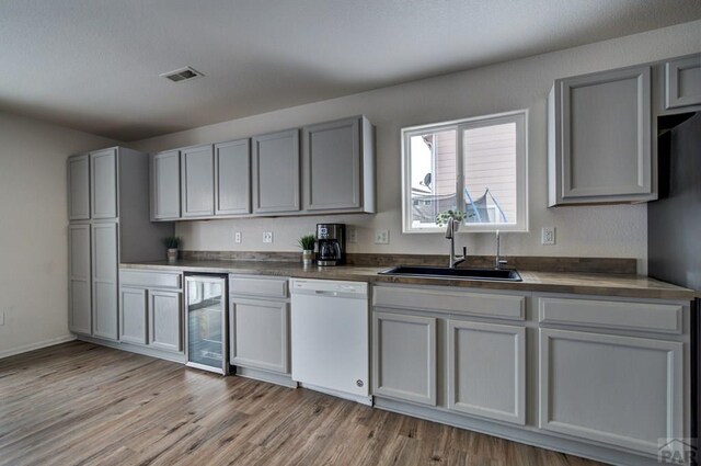 kitchen with dishwasher, wine cooler, a sink, and gray cabinetry