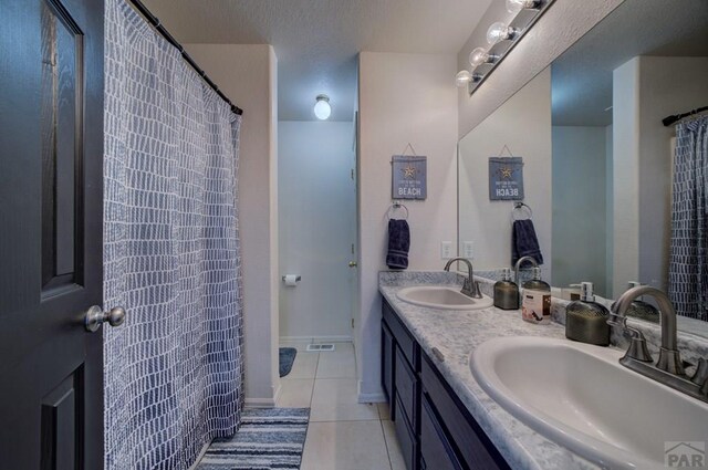 full bathroom with baseboards, double vanity, a sink, and tile patterned floors