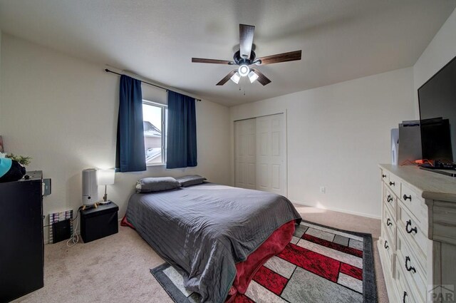 bedroom with a ceiling fan, a closet, and light colored carpet