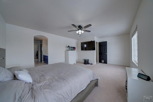 bedroom featuring light carpet, arched walkways, and a ceiling fan