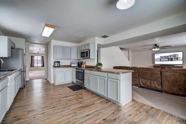 kitchen featuring visible vents, dark countertops, light wood-style flooring, appliances with stainless steel finishes, and open floor plan