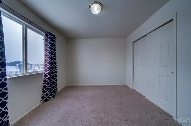 bedroom featuring a closet, light carpet, and baseboards