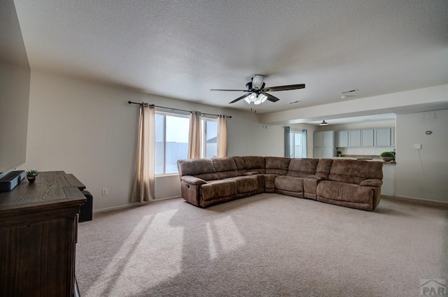 living room with light carpet, ceiling fan, baseboards, and a textured ceiling