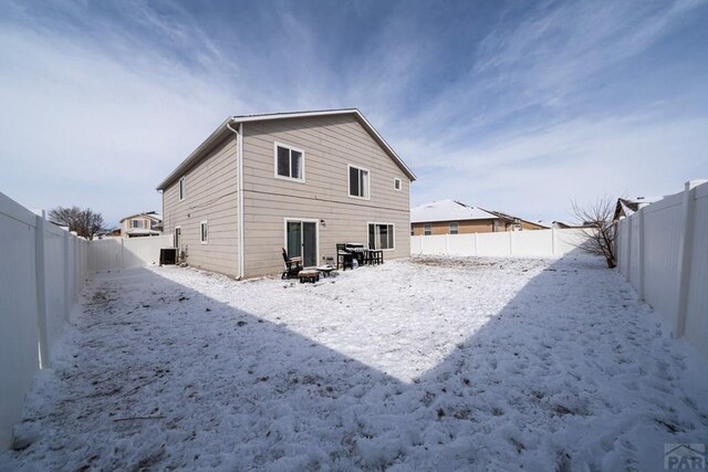 snow covered property with central AC unit and a fenced backyard