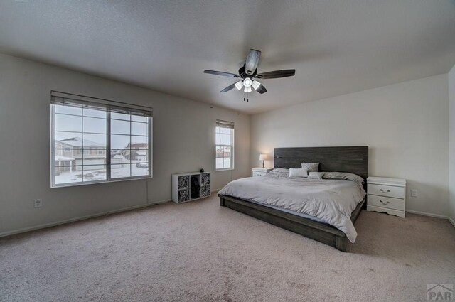 carpeted bedroom with ceiling fan and baseboards