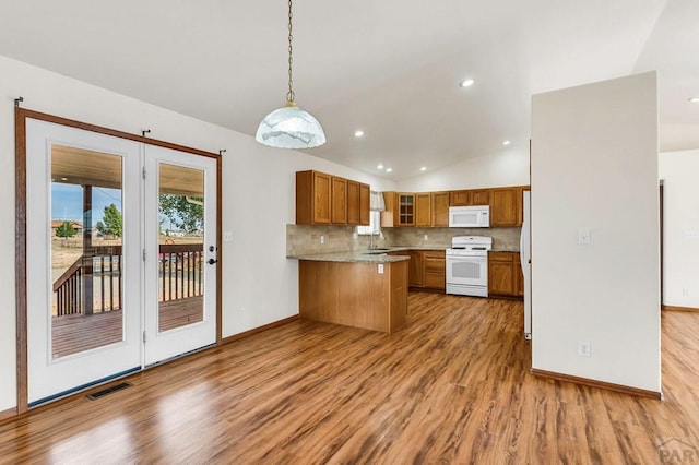 kitchen with brown cabinets, decorative light fixtures, a sink, white appliances, and a peninsula