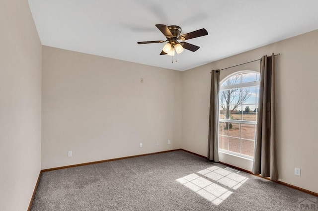 spare room featuring carpet floors, visible vents, baseboards, and a ceiling fan