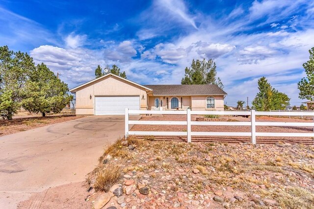 ranch-style house featuring a garage, concrete driveway, fence, and stucco siding