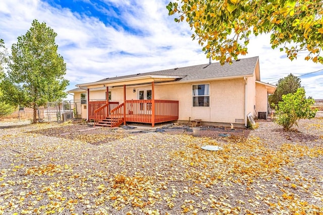 rear view of property featuring fence, a deck, and stucco siding