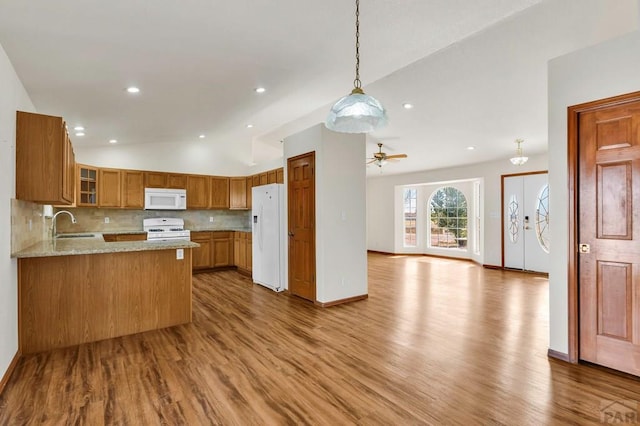 kitchen with white appliances, glass insert cabinets, open floor plan, a peninsula, and vaulted ceiling