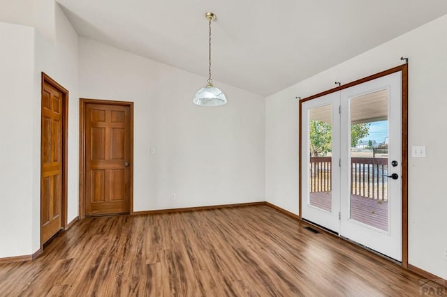 unfurnished dining area featuring lofted ceiling, visible vents, baseboards, and wood finished floors