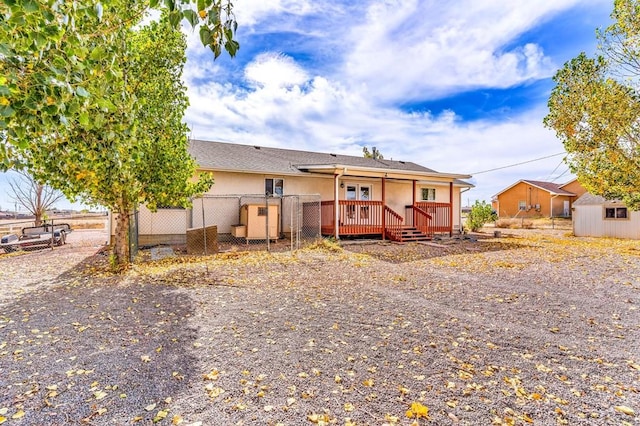 view of front facade featuring stucco siding, fence, a storage unit, and a wooden deck