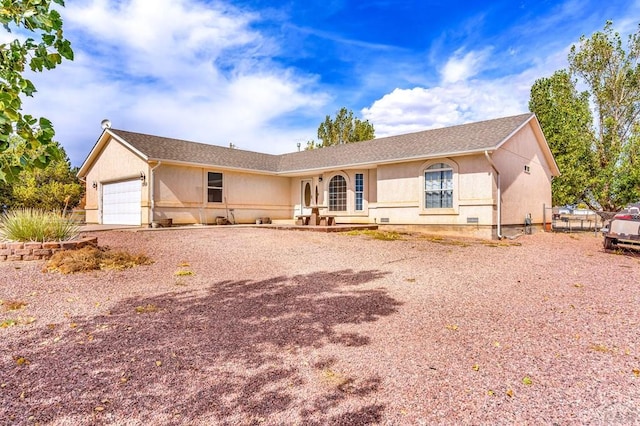 single story home featuring a garage, gravel driveway, and stucco siding