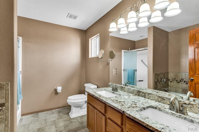 bathroom featuring double vanity, stone finish floor, a sink, and visible vents