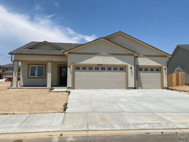 single story home featuring a garage, driveway, a shingled roof, fence, and stucco siding