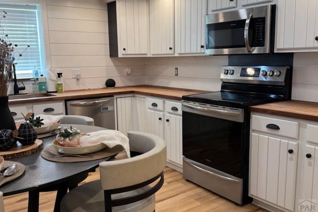 2202 W 15th St, Pueblo, CO 81003 - kitchen featuring stainless steel appliances, butcher block countertops, light wood-type flooring, and white cabinets