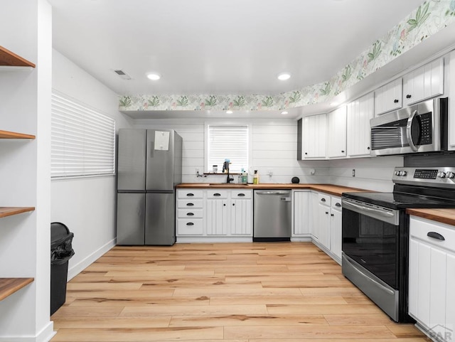 2202 W 15th St, Pueblo, CO 81003 - kitchen with stainless steel appliances, wooden counters, open shelves, light wood-style floors, and white cabinets