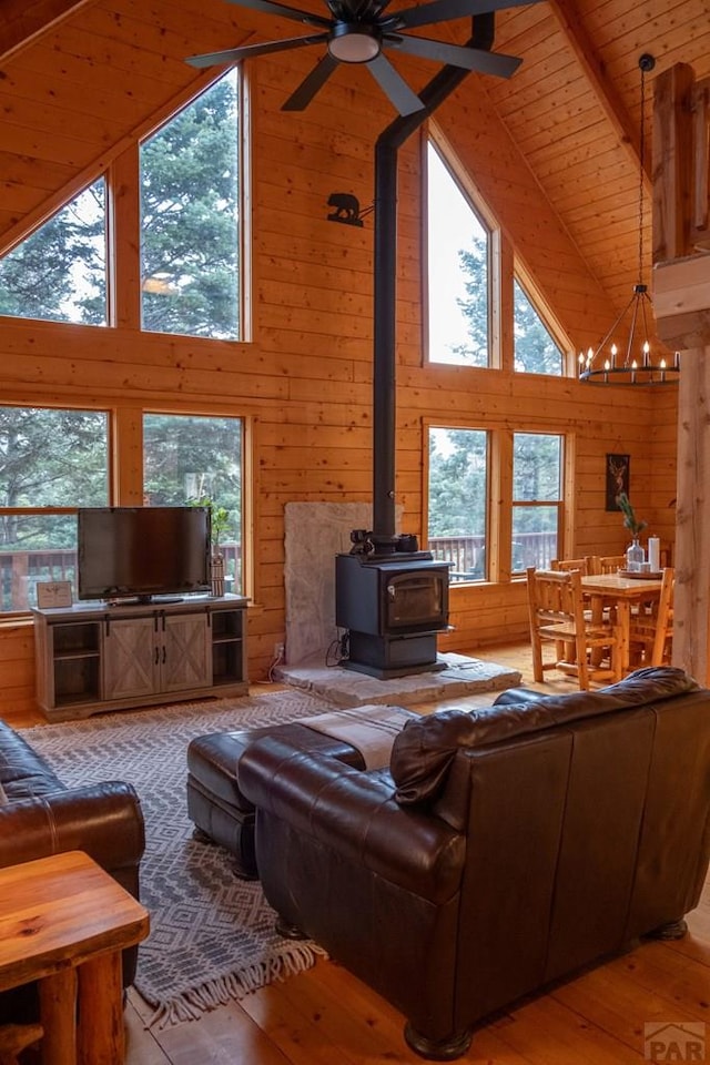 317 Parsons Rd, La Veta, CO 81055 - living area with high vaulted ceiling, a wood stove, wood walls, a ceiling fan, and hardwood / wood-style flooring