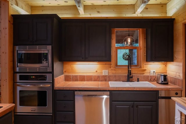 317 Parsons Rd, La Veta, CO 81055 - kitchen with stainless steel appliances, tile countertops, a sink, wood walls, and beam ceiling