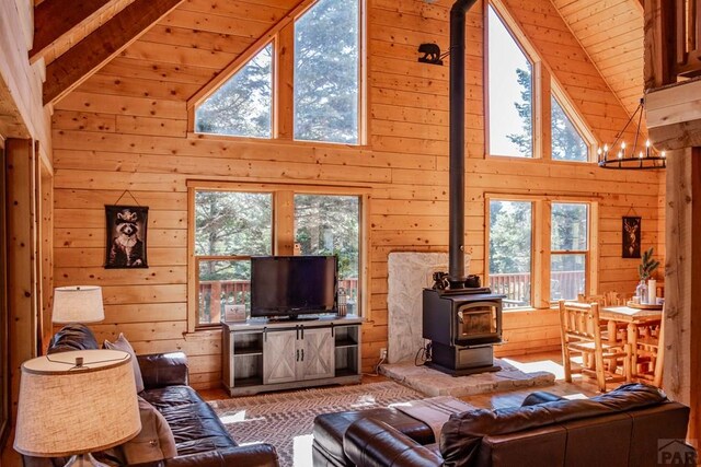 317 Parsons Rd, La Veta, CO 81055 - living room featuring a wood stove, wood walls, healthy amount of natural light, high vaulted ceiling, and wood ceiling