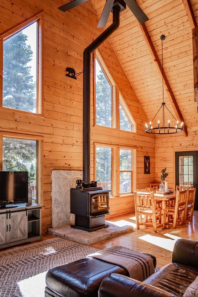 317 Parsons Rd, La Veta, CO 81055 - living room featuring high vaulted ceiling, wood walls, a wood stove, a chandelier, and hardwood / wood-style floors