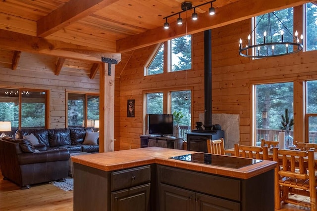 317 Parsons Rd, La Veta, CO 81055 - kitchen with tile counters, open floor plan, a wood stove, wood ceiling, and wooden walls