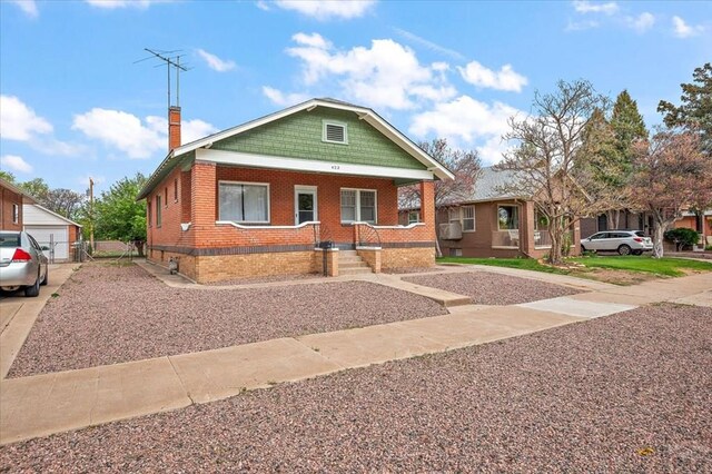 423 Washington St, Pueblo, CO 81004 - bungalow-style home featuring brick siding, a chimney, gravel driveway, and covered porch
